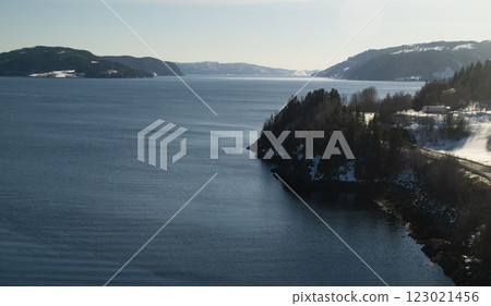 A serene winter landscape featuring a deep blue fjord 123021456