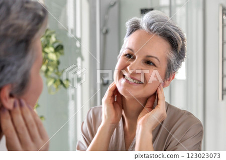 Smiling woman of the age with gray hair does herself a manual facial massage and face fitness 123023073