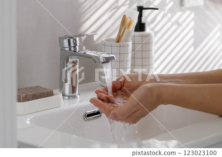 Woman washing female hands close up in washbasin with clean running water. Woman washing female hands close up in washbasin with clean running water. 123023100