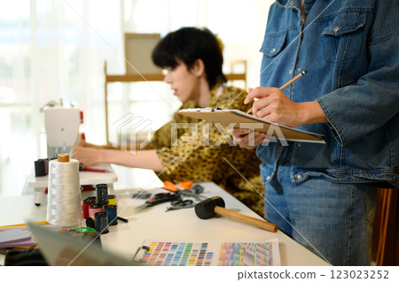 Cheerful fashion entrepreneurs designing new collection in a home studio Cheerful fashion entrepreneurs designing new collection in a home studio 123023252