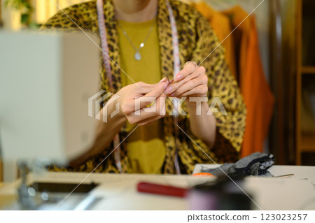 Close up of fashion designer threading needle, preparing for sewing work 123023257