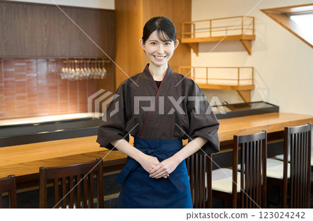 A Japanese restaurant employee smiling inside the restaurant A Japanese restaurant employee smiling inside the restaurant 123024242