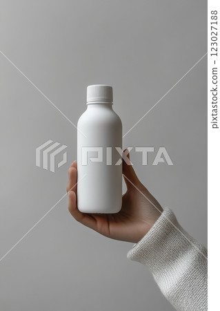 Hand holding a minimalist white bottle indoor setting product photography neutral background close-up contemporary design Hand holding a minimalist white bottle indoor setting product photography neutral background close-up contemporary design 123027188