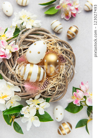 Easter eggs are lying in a nest with spring flowers on a gray background 123027493