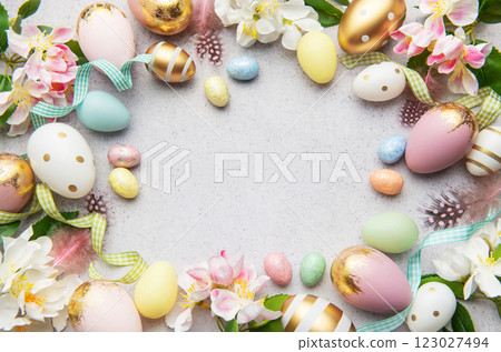 Easter eggs frame forming a circle on a gray background with flowers and feathers 123027494