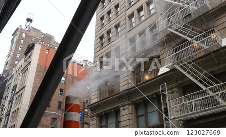 Steam vapor vented, New York City street steam system, orange vapour tube stack. Hot smoke from pipe 123027669