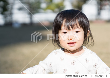 A one-year-old Japanese girl playing on the grass in a park A one-year-old Japanese girl playing on the grass in a park 123028391