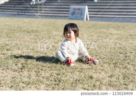 A one-year-old Japanese girl playing on the grass in a park 123028409