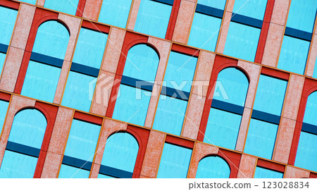 The geometric facade blends symmetry and contrast, with vivid blue windows framed by textured red arches. The tilted angle enhances the rhythmic pattern of repetition. The geometric facade blends symmetry and contrast, with vivid blue windows framed by textured red arches. The tilted angle enhances the rhythmic pattern of repetition. 123028834