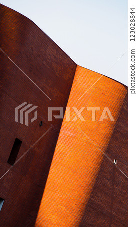 Curved brick architecture illuminated by sunlight creates a striking contrast between warm and shadowed tones. 123028844