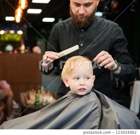 Cute boy getting stylish haircut. Hairdresser in process. Little client first time in barbershop. 123028862