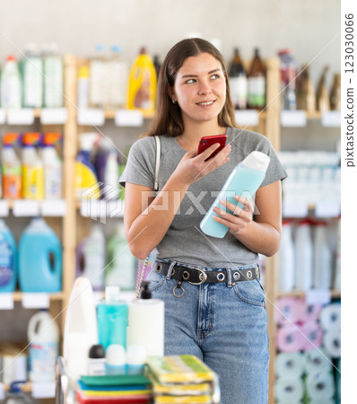 Young woman scanning qr code for shampoo or shower gel 123030066