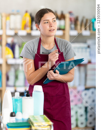 Female supervisor taking notes during inventory in cleaning and hygiene products store 123030094