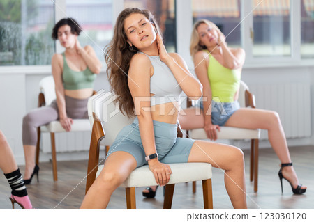 Young woman performing sass dance movements with chair at group class 123030120