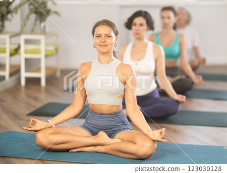 Smiling girl meditating in lotus position in yoga studio 123030128