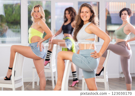Group of girls unleash their energy and dance passionately near a chair in high heels in a dance studio. His powerful moves combined with elegance of high heels 123030170