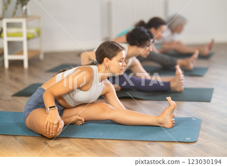 Young girl stretching in Janu Sirsasana during group yoga practice 123030194