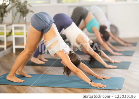 Woman doing downward facing dog pose at group yoga training 123030196