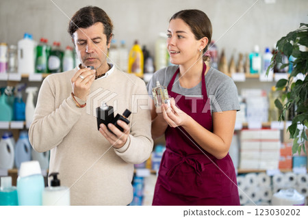 Saleswoman offers man to buy fragrant perfume in supermarket 123030202