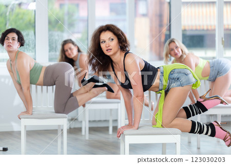 Women during dance lesson perform dance number in high heels. Rehearsal of modern high heels dances with elements of strip plastics 123030203