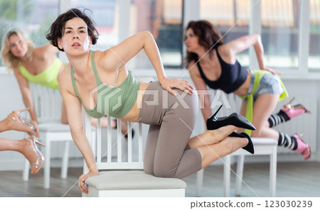 Women during dance lesson perform dance number in high heels. Rehearsal of modern high heels dances with elements of strip plastics 123030239