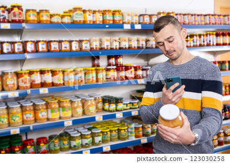 Adult man with mobile phone chooses sauerkraut Adult man with mobile phone chooses sauerkraut 123030258