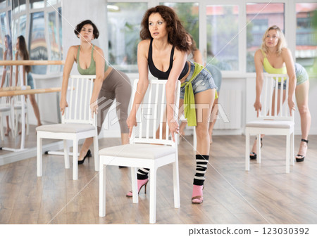 Slender women rehearse modern dances using chair Slender women rehearse modern dances using chair 123030392