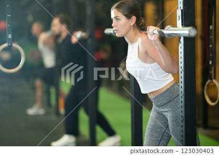 Determined young girl working out with gym rod during crossfit workout Determined young girl working out with gym rod during crossfit workout 123030403