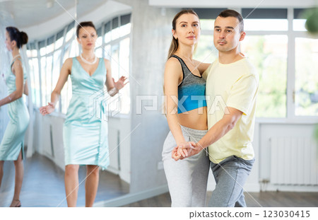 Couple in comfortable sports clothes waltz dancing during individual lesson Couple in comfortable sports clothes waltz dancing during individual lesson 123030415