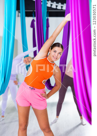Girl doing warming up among hanging hammocks for anti-gravity yoga 123030571