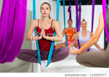 Young woman doing Bhadrasana asana in hanging hammock with hands in namaste 123030577
