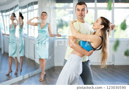 Couple in comfortable sports clothes waltz dancing during individual lesson Couple in comfortable sports clothes waltz dancing during individual lesson 123030590