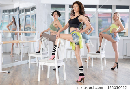 Woman in high heels practicing lap dance with chair during group class Woman in high heels practicing lap dance with chair during group class 123030612