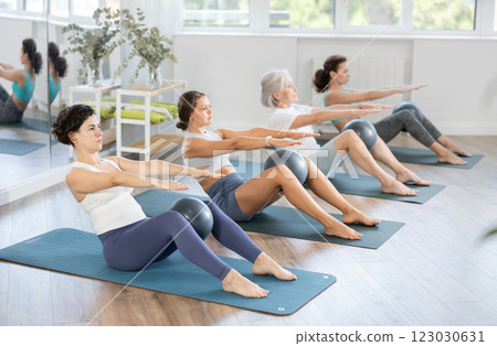Adult woman doing pilates with soft ball in group Adult woman doing pilates with soft ball in group 123030631