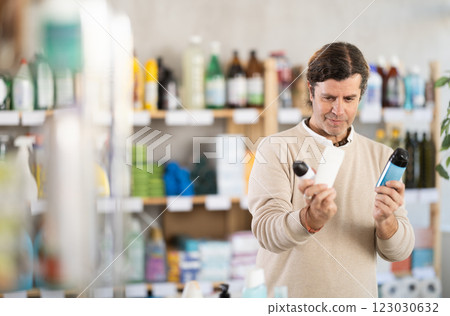Man chooses deodorant aerosol can or air freshener in supermarket Man chooses deodorant aerosol can or air freshener in supermarket 123030632