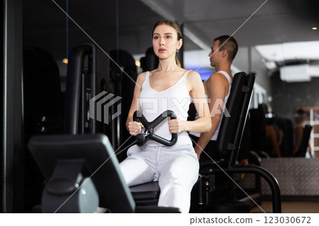 Sportive young girl training her arms using cable exercise machine in gym Sportive young girl training her arms using cable exercise machine in gym 123030672