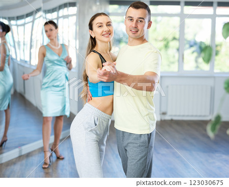 Positive couple practicing slow foxtrot in dance studio 123030675