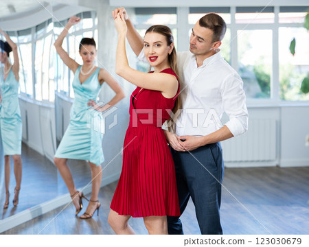 Woman in red dancing passionate bachata with man at dance class 123030679