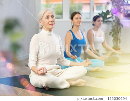 Woman making yoga meditation in lotus pose in modern fitness studio Woman making yoga meditation in lotus pose in modern fitness studio 123030694