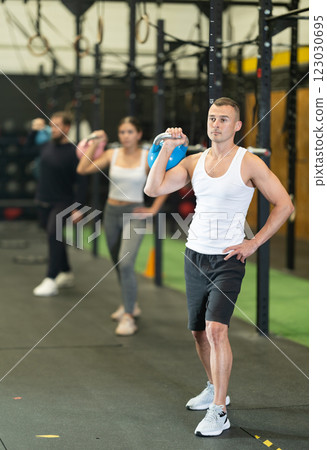 Sporty young man exercising with kettlebell in gym at group workout 123030695