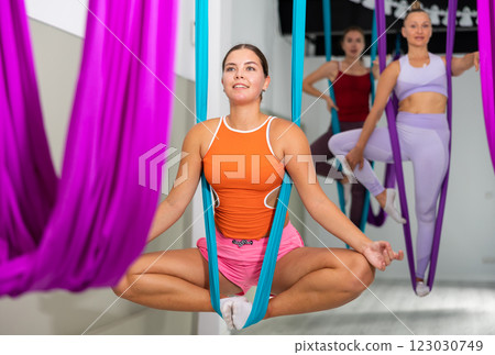 Girl doing Baddha Konasana asana in suspended hammock with hands in mudra 123030749