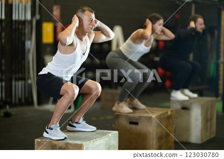 Man jumping up on box at functional cross training in gym Man jumping up on box at functional cross training in gym 123030780