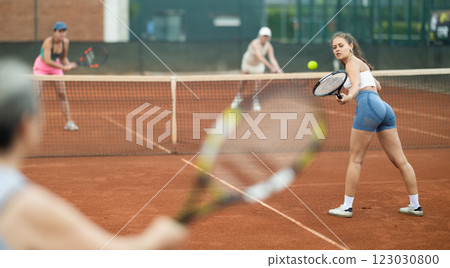 Young and elderly women playing doubles tennis Young and elderly women playing doubles tennis 123030800