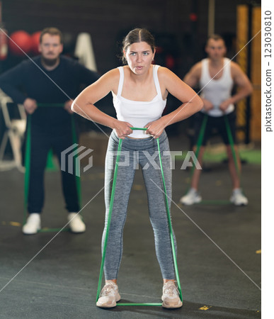 Determined young girl working out with resistance band in gym 123030810