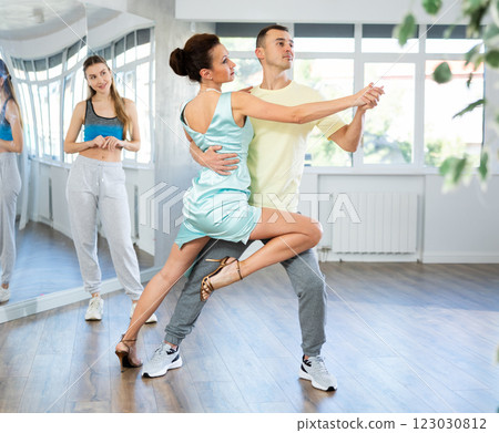 Coach, paired with man student, shows master class and explains technique of tango dance 123030812