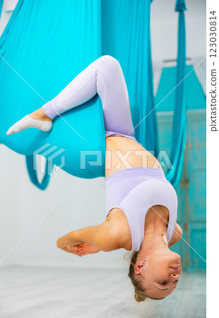 Group of women hang upside down in a hammock. Fly yoga class in gym. Fit and wellness lifestyle 123030814
