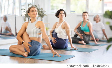 Group of women of different ages working out practice Lord of fishes pose 123030857