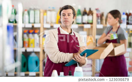 Male salesman makes notes on paper - keeps track of the receipt and expenditure of goods in supermarket 123030879