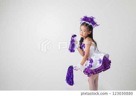 Cheerful young cheerleader girl in a purple and white outfit, holding pom-poms. Energetic studio shot on a white background, full of joy and excitement. cheerleader kid 123030880