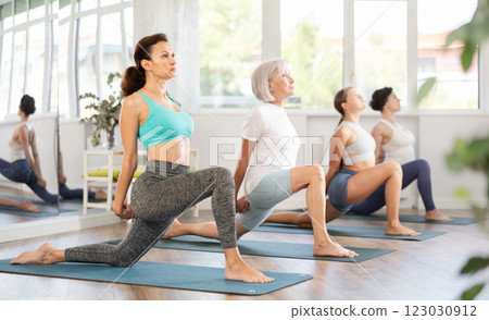 Woman performing Low Lunge Pose at group yoga session 123030912